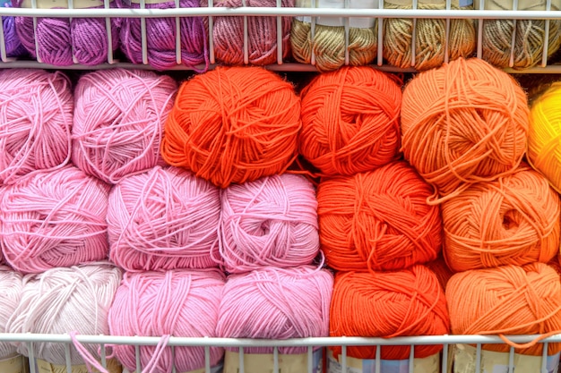 Counter in shop for knitting and needlework with coils colored wool yarn. Different bright colors threads on rows in store. Retail trade of goods for hobby, needlework and knitting. Selective focus