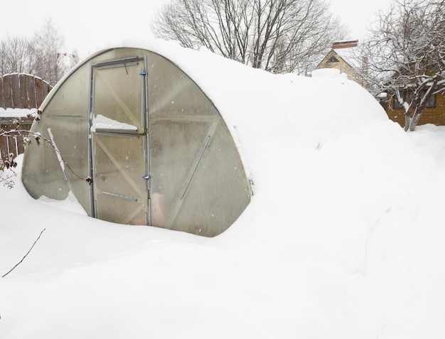 country greenhouse made of polycarbonate covered with snow