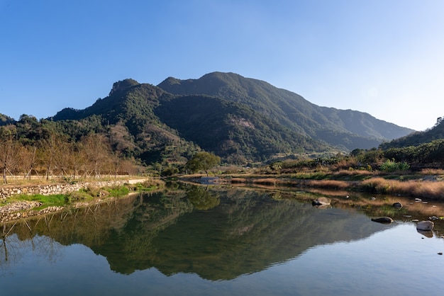 The country river reflects the mountain, and the villages and forests are under the blue sky