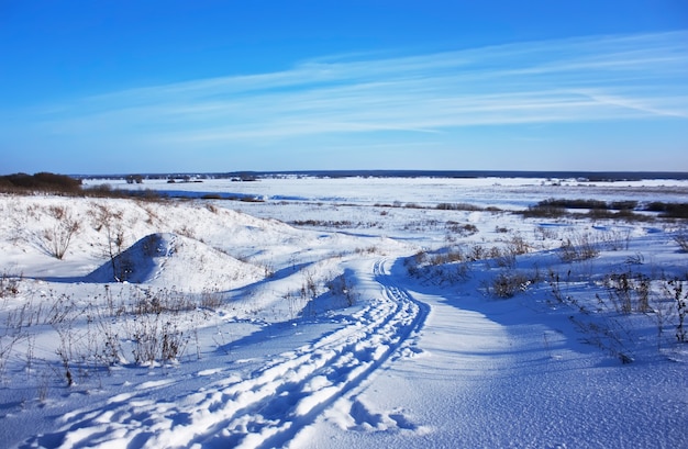 Проселочная дорога, покрытая снегом в зимнем поле