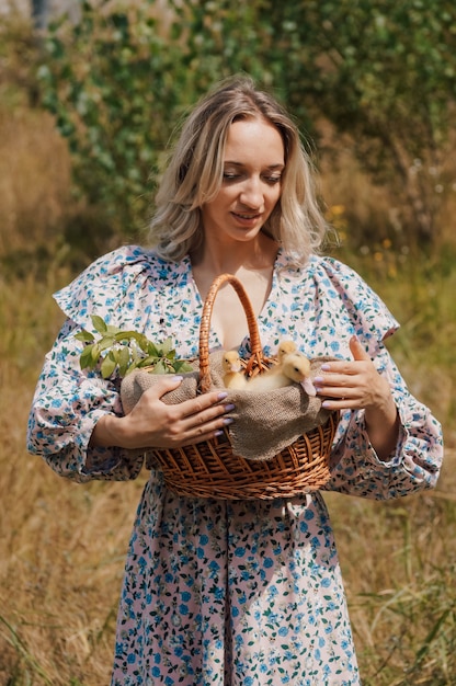 Country woman carries yellow ducklings in a basket