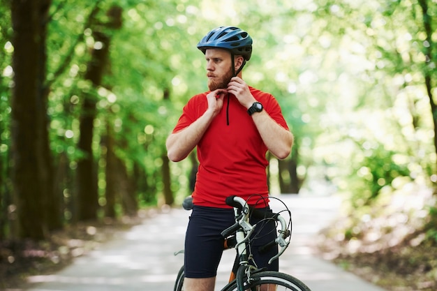 At countryside. Cyclist on a bike is on the asphalt road in the forest at sunny day