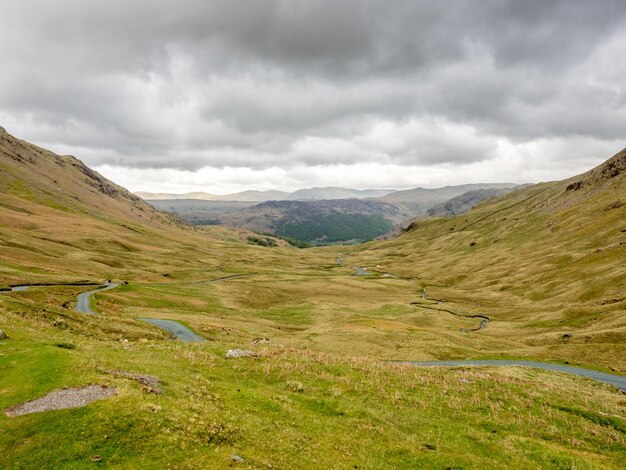 영국의 흐린 하늘 아래 녹색 들판과 산 배경의 시골 풍경 보기