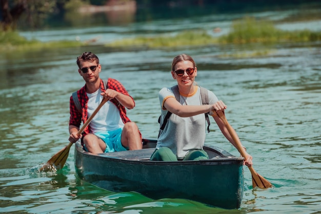Пара предприимчивых друзей-исследователей плывут на каноэ по дикой реке в окружении красивой природы.
