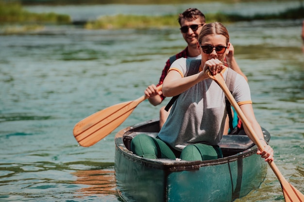 모험을 좋아하는 몇 명의 탐험가 친구들이 아름다운 자연으로 둘러싸인 야생 강에서 카누를 타고 있습니다.