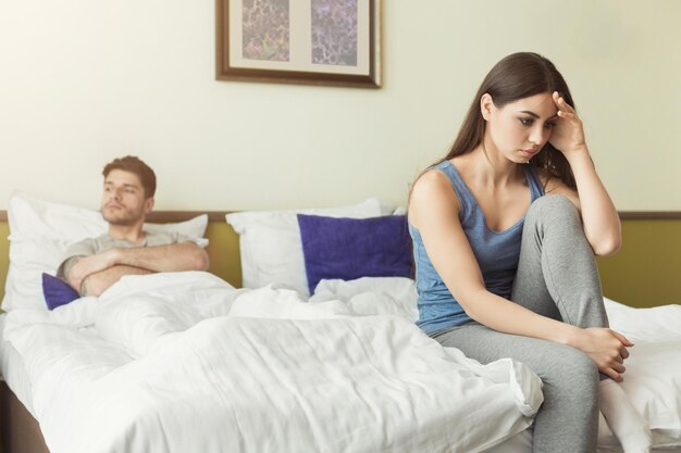 Couple after quarrel sitting in bed sad woman having a headache