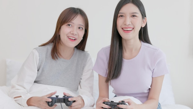 コントローラーを持って一緒にビデオゲームをプレイしている面白い若い女性のカップルカップルがゲームをプレイしていて、そのうちの1人がこのラウンド面白いビデオゲームのコンセプトを勝ち取るために不正行為をしています