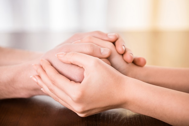 Couple are holding hands on the table.