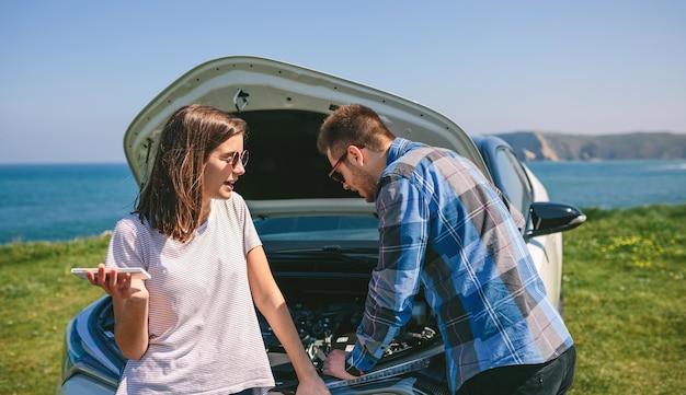 壊れた車を修理しながら口論するカップル