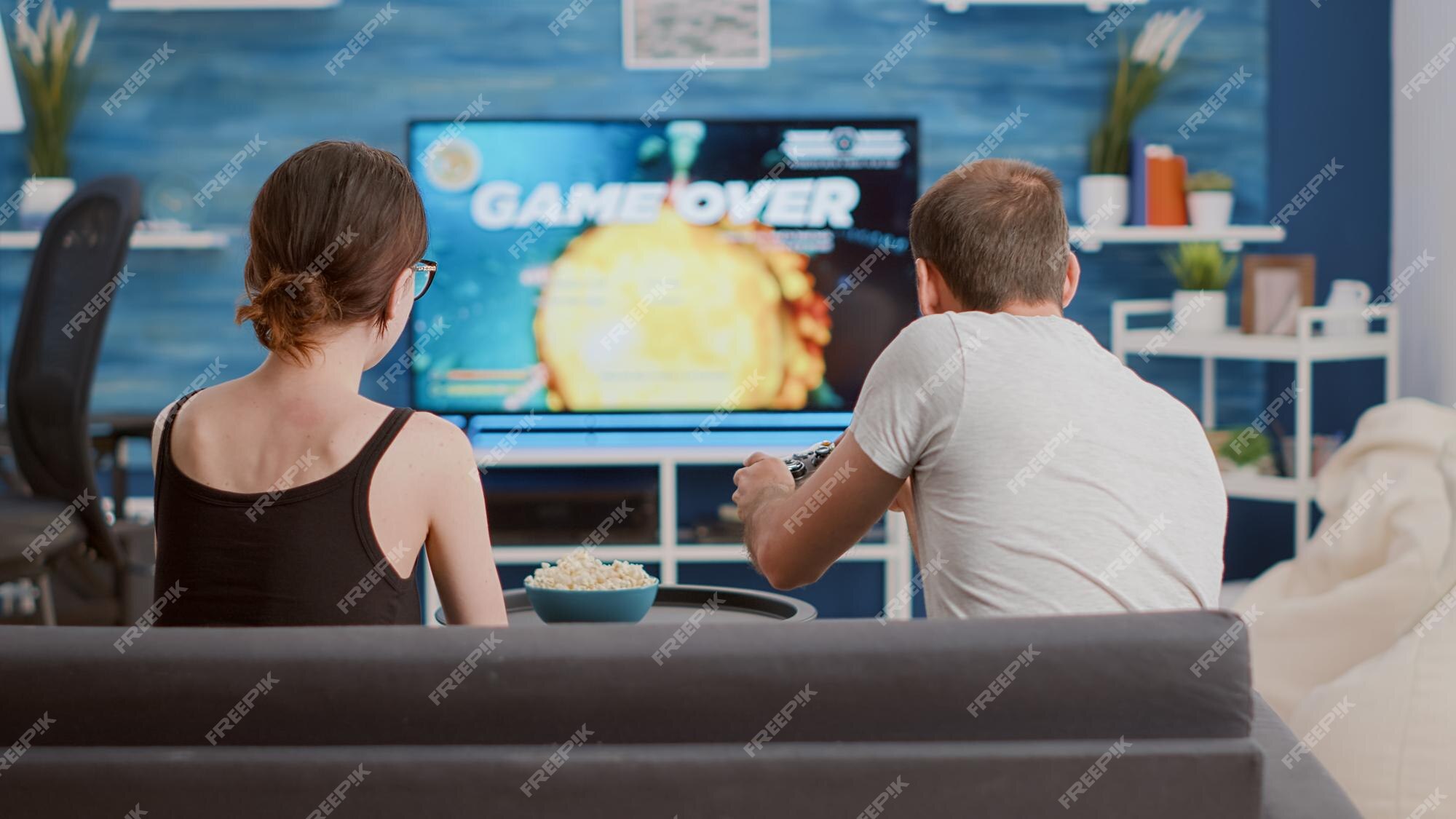 Man beating woman at video games with controller on console over blue  background. Boyfriend celebrating win and girlfriend feeling disappointed  about losing online gameplay in studio Stock Photo - Alamy