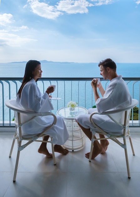 Couple of asian women and caucasian men drinking coffee in\
hotel in thailand