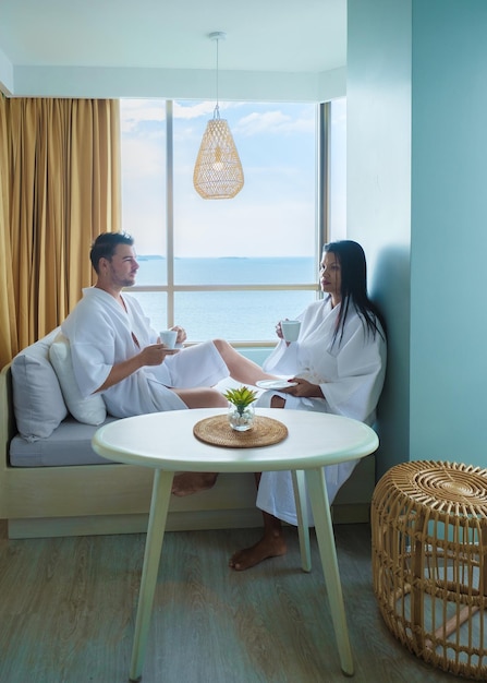 Couple of asian women and caucasian men drinking coffee in\
hotel in thailand