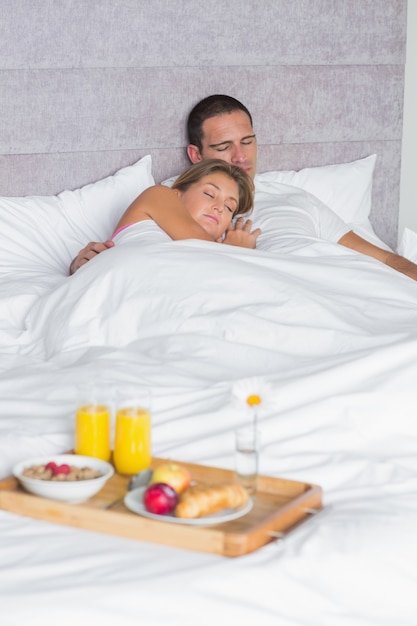 Couple asleep with breakfast tray on bed