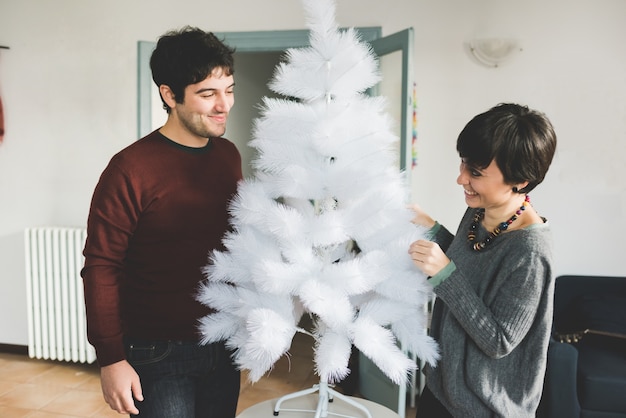 couple assembling christmas tree on a small table 