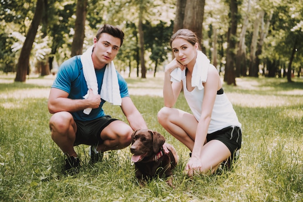 Foto coppia di atleti con il loro cane nel parco verde