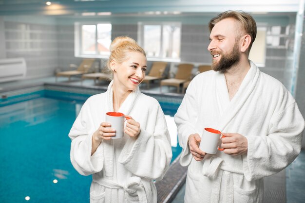 Couple in bathrobes relaxing in the spa near the basin during their holidays