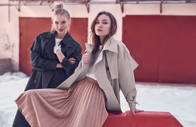 Couple beautiful hipster girls wearing long fashion coats on the street