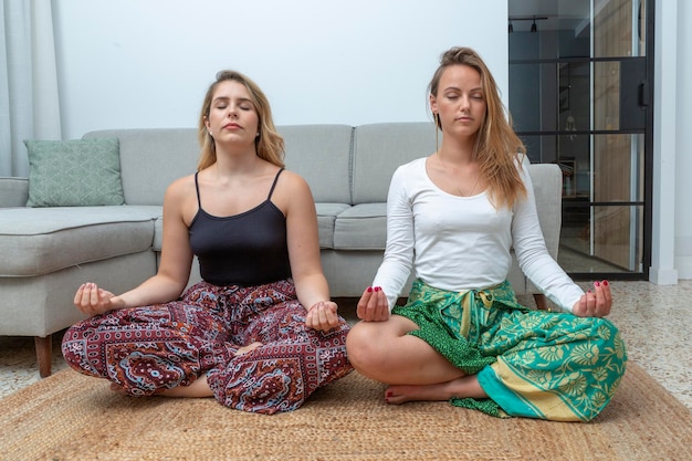 Couple of beautiful women doing meditation at home with palo santo