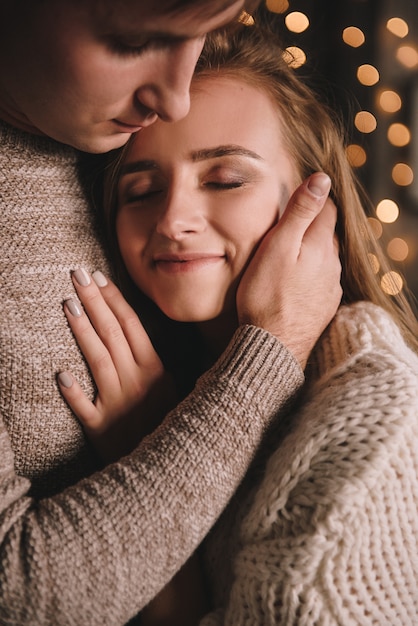 Couple in the bedroom. Dark interior. New Year's and Christmas. Hugs and kisses. Love. White sweater and high socks. Romantic meeting. A date lovers.