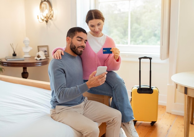 Couple booking room using credit card and phone in hotel