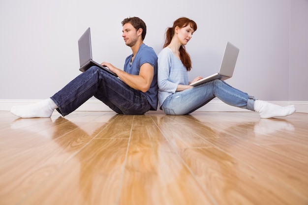 Couple both using laptops separately  