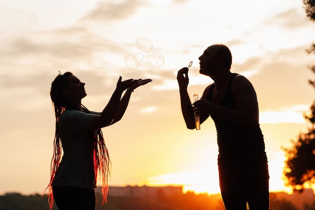 Couple bubble blowing silhouette nature concept. Unity with the nature.