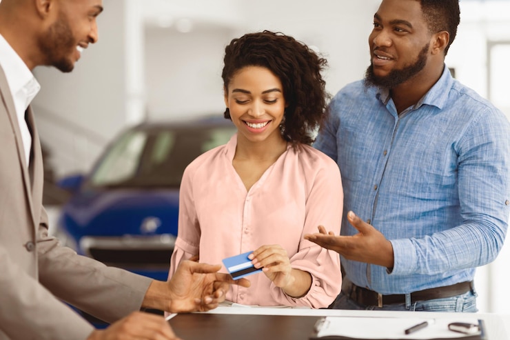 Photo couple buying car giving credit card to salesman in dealership