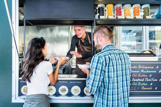 Couple buying pasta from food truck at outdoor market