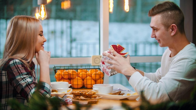 A couple in cafe a man gives his girlfriend a little christmas gift