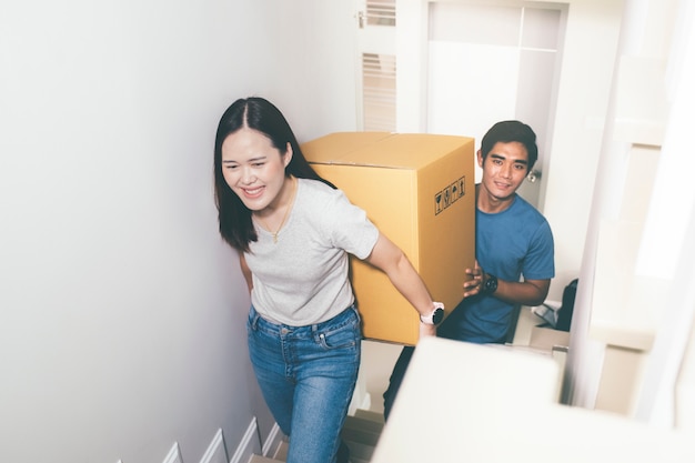 Couple carrying heavy moving boxes together.