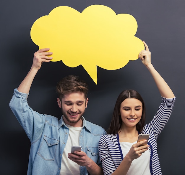 Couple in casual clothes is holding a yellow speech bubble.