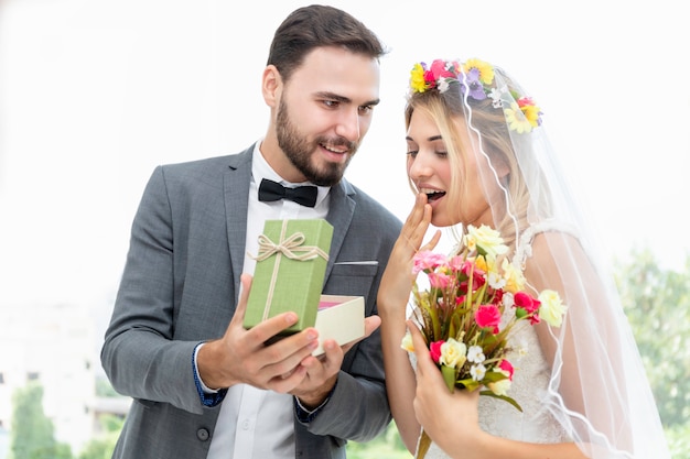 Coppia di caucasici, sposo dare presente sposa in studio di nozze.