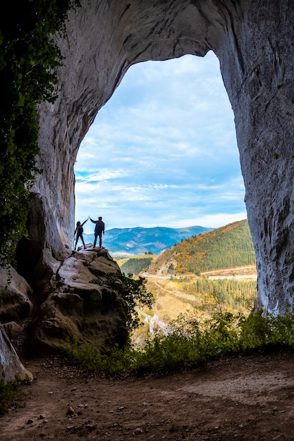 A couple in the caves of Ojo de Aitzulo in Oñati with arms raised