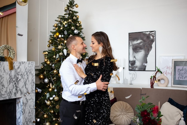 Foto coppie che celebrano felicemente il natale e le feste vicino al concetto di natale dell'albero di natale splendidamente decorato