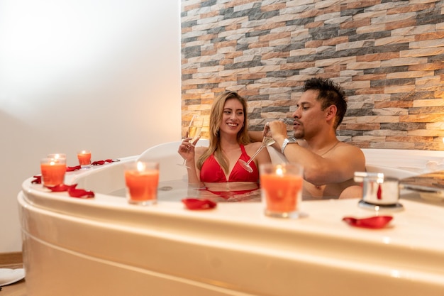 Coppia che festeggia una serata romantica per san valentino in un hotel con vasca idromassaggio.