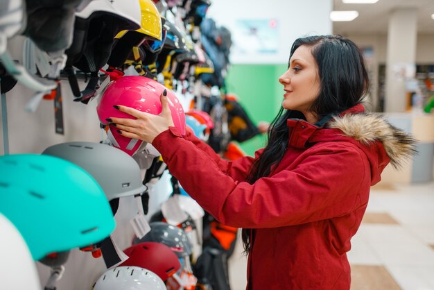 Couple choosing helmets, shopping in sports shop