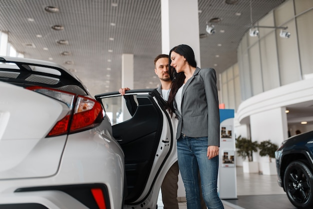 Couple choosing new car in showroom.