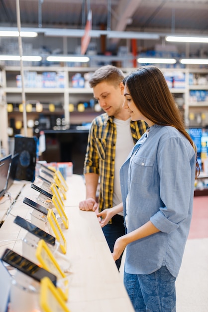 Couple choosing phones in electronics store