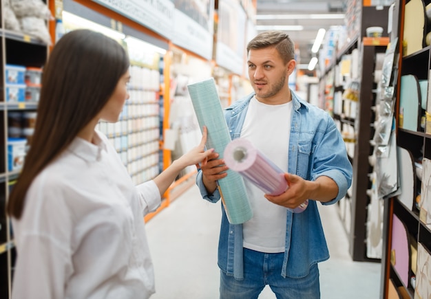 Couple choosing wallpapers color in hardware store