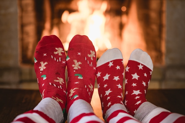 Couple in Christmas socks near fireplace Man and woman having fun together