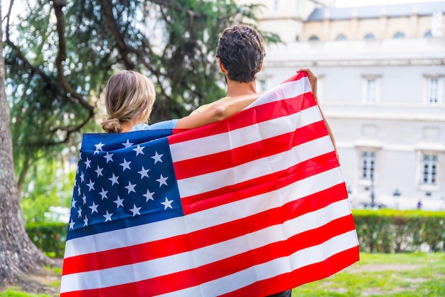 Couple in the city with usa flag boy and girl on their backs Patriots proud of their nation independence day