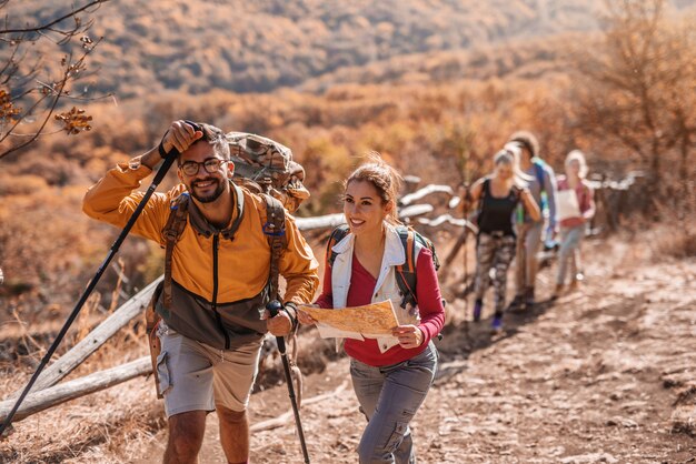 Couple climbing the hill and talking. Woman holding map.