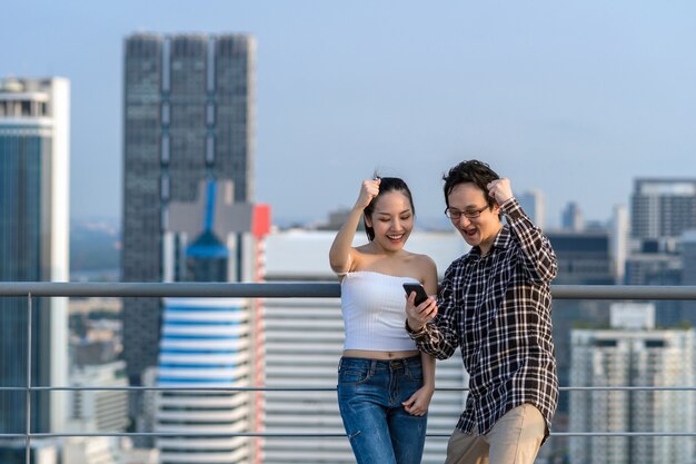 Couple colleague businessman and woman in casual suit are celebrating with the success via smart mob