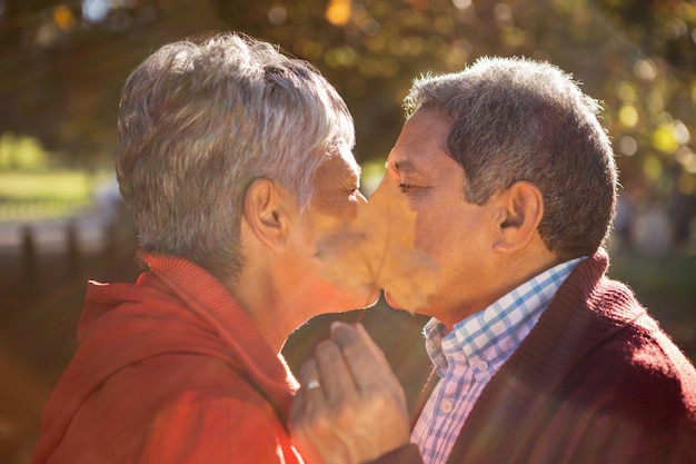 Пара закрывает лицо листком во время поцелуя