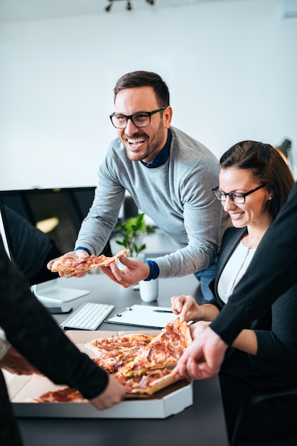 Couple of coworkers having lunch break, eating pizza.