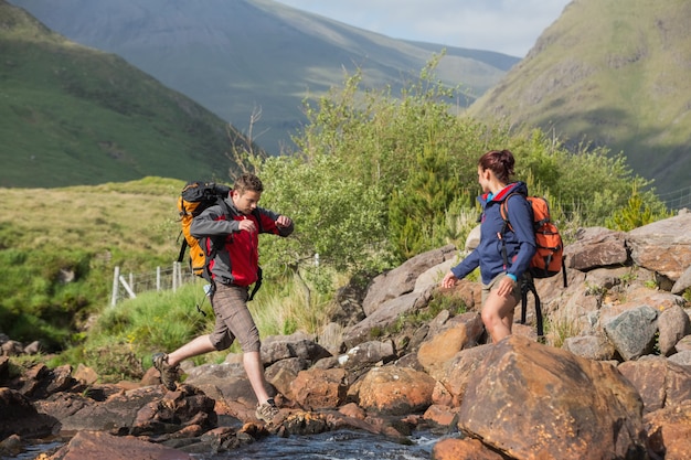 Couple crossing a river on a hike