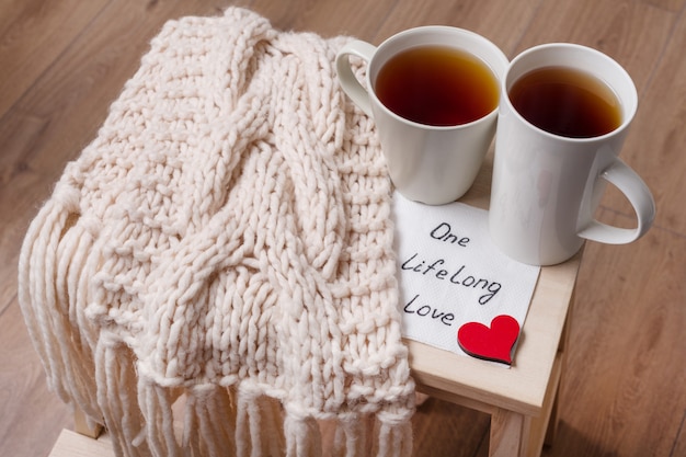 Couple of cups, warm scarf, in home interior