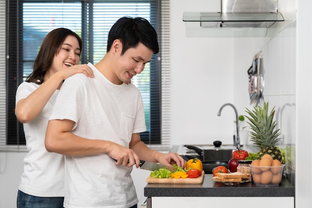 사진 집에서 부엌에서 건강한 음식을 준비하기 위해 야채를 자르는 커플 남자에게 마사지를 하는 여자