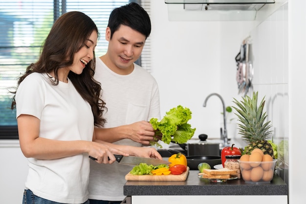 Couple cutting vegetables for preparing healthy food in the kitchen at home