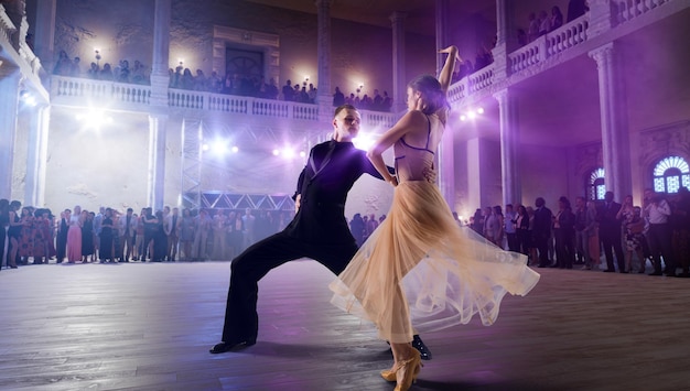 カップル ダンサーが大規模なプロのステージ社交ダンスでワルツを実行します。